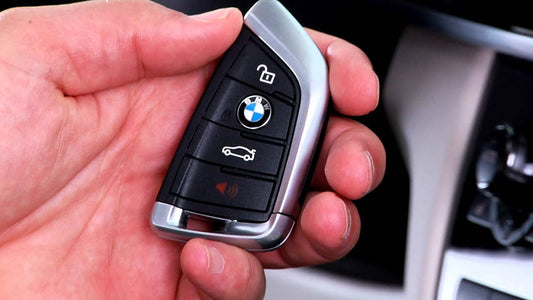BMW key fob held in hand, used to start the engine remotely with three presses of the lock button